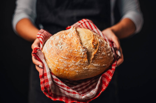 cropped shot of woman holding freshly baked bread in hands - Foto, Imagen