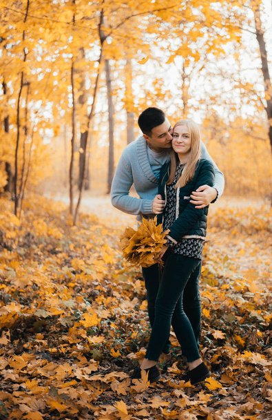 beautiful happy young couple standing together and hugging in autumn forest - Fotoğraf, Görsel