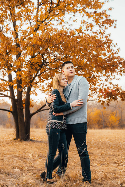 beautiful happy young couple standing together and hugging in autumn park - Photo, Image