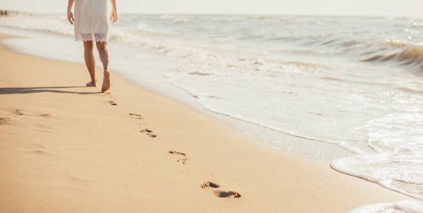 cropped shot of young barefoot woman walking on sandy beach - Foto, Imagen