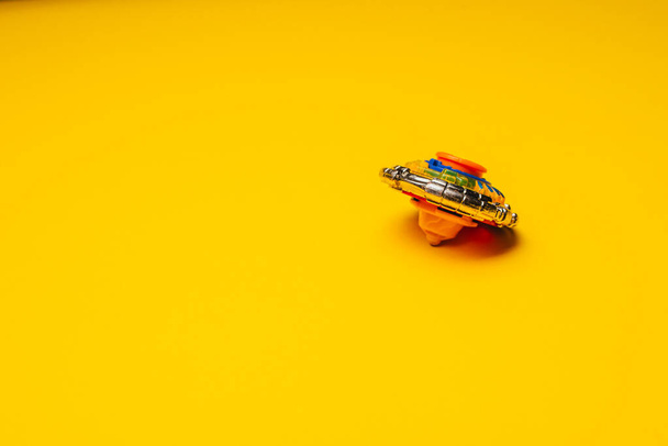 close-up view of modern spinning Beyblade toy on yellow background - Foto, Bild