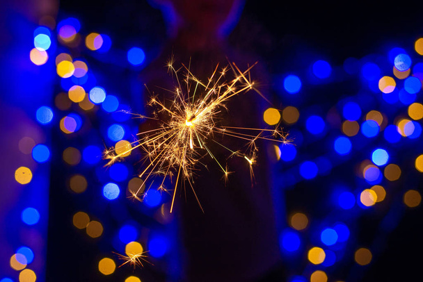 festive christmas background with person holding burning sparkler - 写真・画像