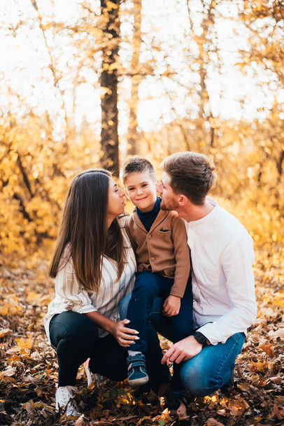 familia joven y feliz con un niño pasando tiempo juntos en el parque de otoño
 - Foto, Imagen