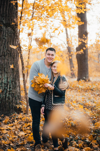 beautiful happy young couple standing together and hugging in autumn park - Foto, imagen