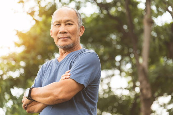 Azji starszy mężczyzna w niebieskiej koszuli uśmiecha się z ramionami skrzyżowane przed  - Zdjęcie, obraz