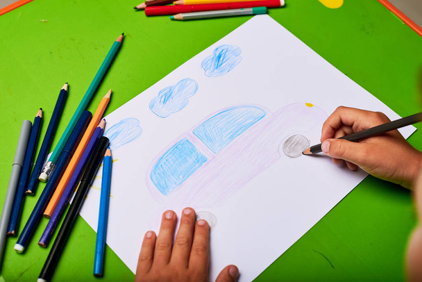 little boy drawing car by pencil at table - Фото, изображение