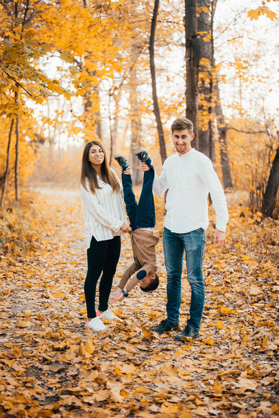 happy young parents having fun with little son in autumn park  - Фото, изображение