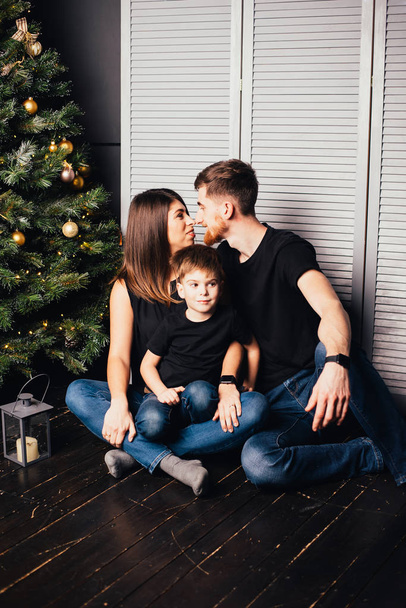 happy young family with one child sitting together near christmas tree - Foto, Imagem