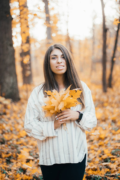 beautiful young woman smiling at camera in autumn forest   - Fotografie, Obrázek