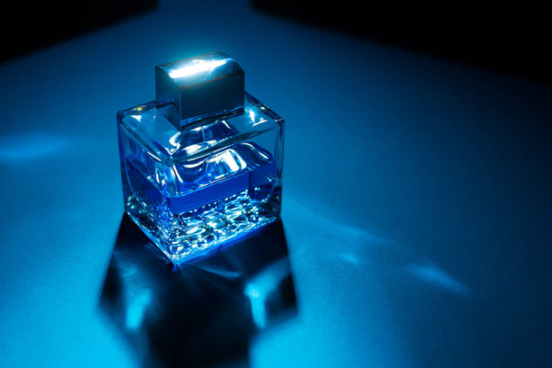 Vista de cerca de la botella de perfume masculino sobre fondo azul y negro
  - Foto, imagen