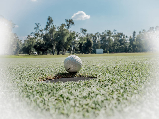 Zdjęcie białej piłki golfowej na trawie z niebieskim tle nieba - Zdjęcie, obraz