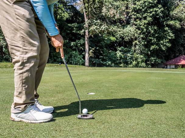 Zdjęcie golfistów wkładają golfa do dołka z miotaczem na zielonej trawie - Zdjęcie, obraz