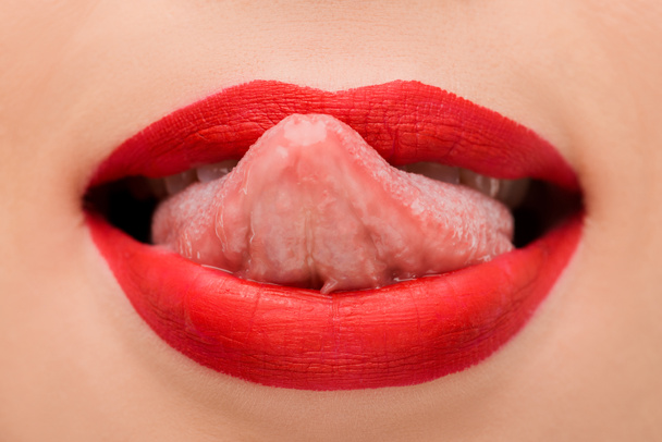 περικοπή άποψη του κοριτσιού με κόκκινο κραγιόν γλείφει τα χείλη απομονώνονται σε λευκό  - Φωτογραφία, εικόνα