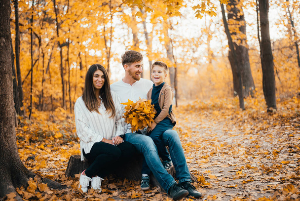 piękne szczęśliwy młodzi rodzice z małym synem spędzają czas razem w jesiennym parku - Zdjęcie, obraz