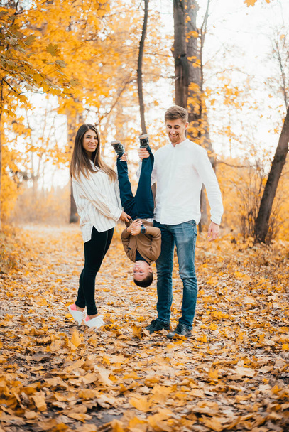 happy young parents having fun with little son in autumn park  - Photo, Image