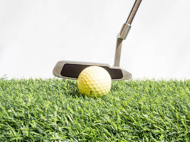 Golf topunu golf sopasıyla suni çimlere ve beyaz arka plana koymak. - Fotoğraf, Görsel