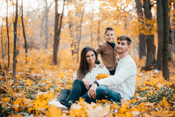 beautiful happy young family with one kid spending time together in autumn park - Foto, Imagem