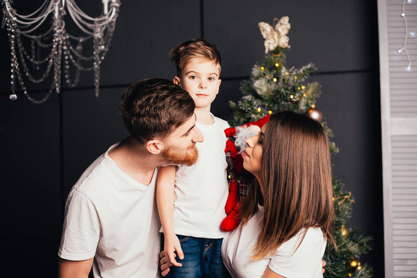 szczęśliwa młoda rodzina z jednym dzieckiem spędzającym razem czas na Boże Narodzenie - Zdjęcie, obraz