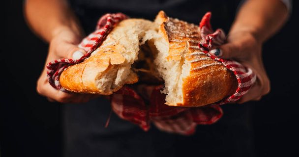 cropped shot of baker holding freshly baked bread in hands - Foto, Imagen