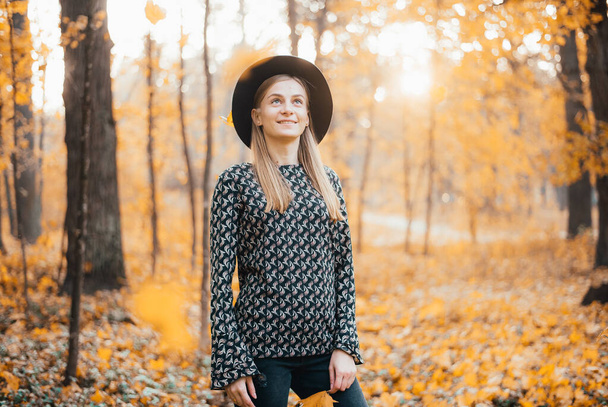 beautiful young woman in hat standing in autumn forest - Fotografie, Obrázek