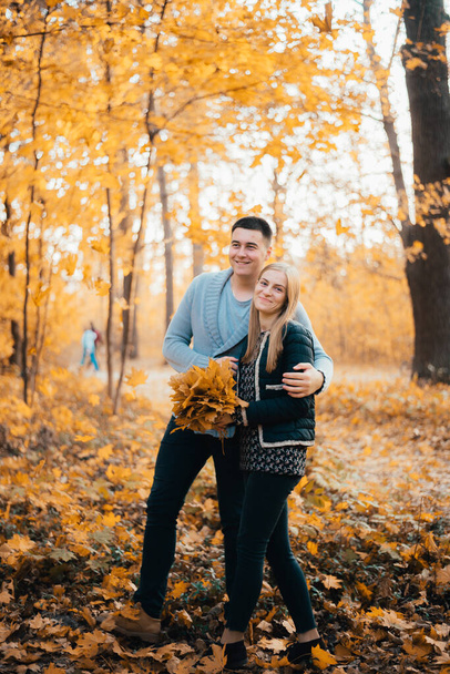 happy young couple standing together and hugging in autumn forest - Φωτογραφία, εικόνα