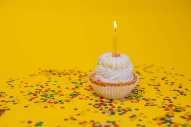 zblízka pohled na lahodný slavnostní cupcake s hořící svíčkou na žlutém pozadí - Fotografie, Obrázek