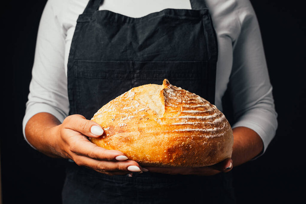 close-up partial view of baker holding freshly baked bread in hands - Фото, зображення