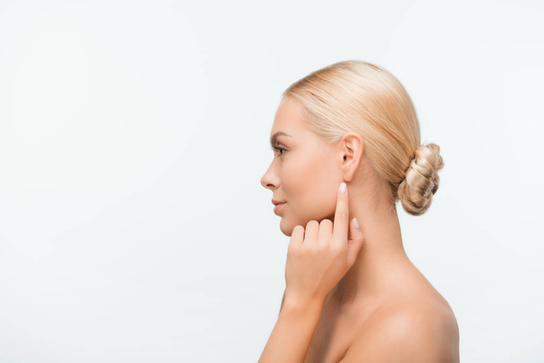 vista lateral de mujer joven desnuda señalando con el dedo en la oreja aislada en blanco
  - Foto, imagen