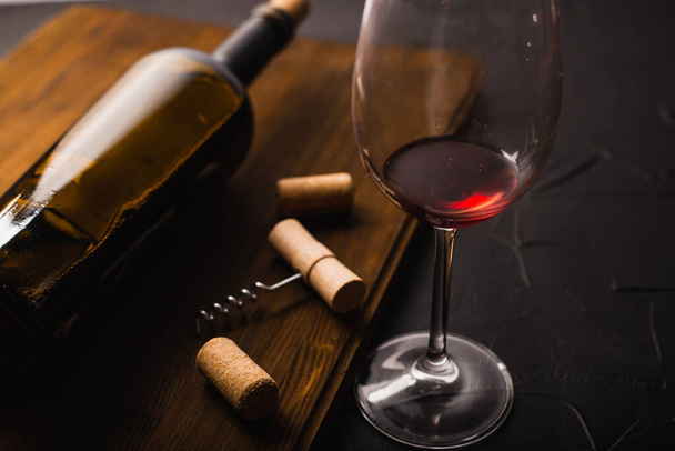 wine bottle, glass and corkscrew with corks on black background  - Φωτογραφία, εικόνα