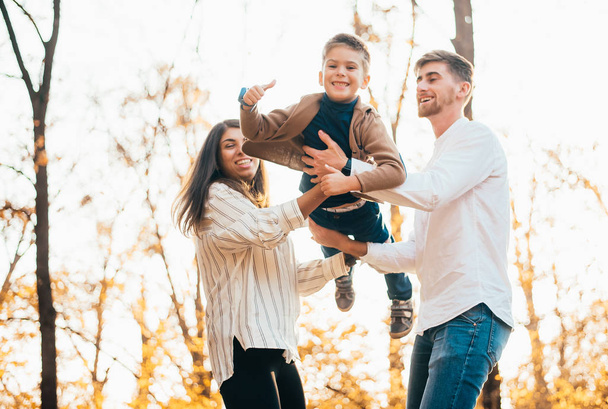 szczęśliwy młody rodzice i słodkie mały syn zabawy razem w jesiennym parku - Zdjęcie, obraz