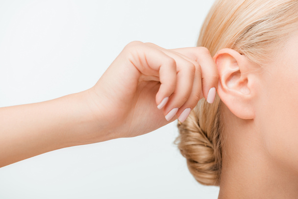 przycięty widok blondynki dotykając ucha podczas słuchania odizolowany na białym  - Zdjęcie, obraz