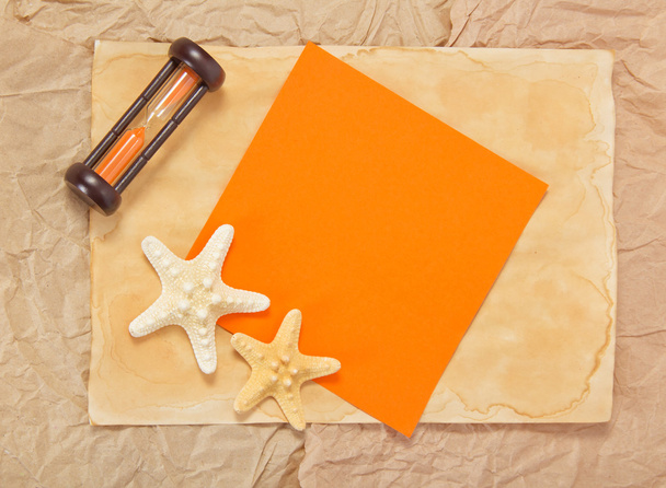 Papel velho, duas estrelas-do-mar, ampulhetas e cartão laranja
 - Foto, Imagem