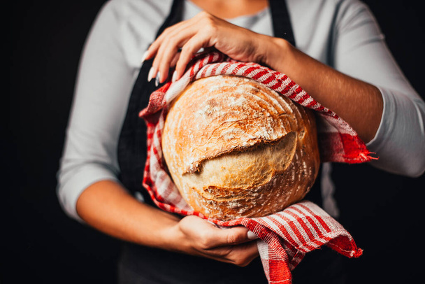 cropped shot of woman holding freshly baked bread in hands - Foto, immagini