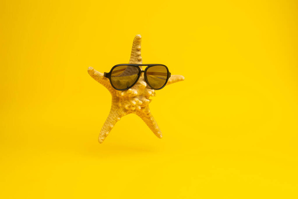 close-up view of funny starfish in sunglasses on yellow background  - Fotó, kép