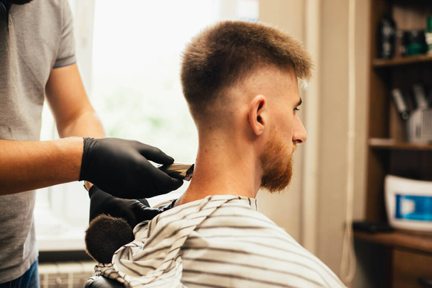 cropped shot of barber shaving hair to man in barbershop - Fotó, kép