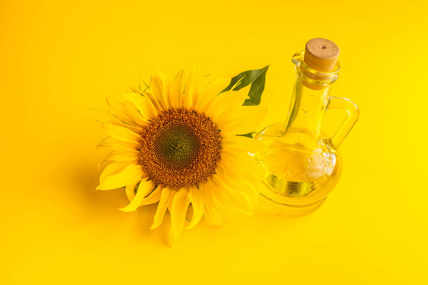 close-up view of beautiful yellow sunflower and bottle of sunflower oil on yellow background - Photo, Image