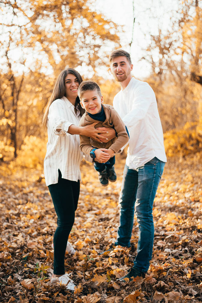 幼い両親とかわいい息子が一緒に楽しい秋の公園で - 写真・画像
