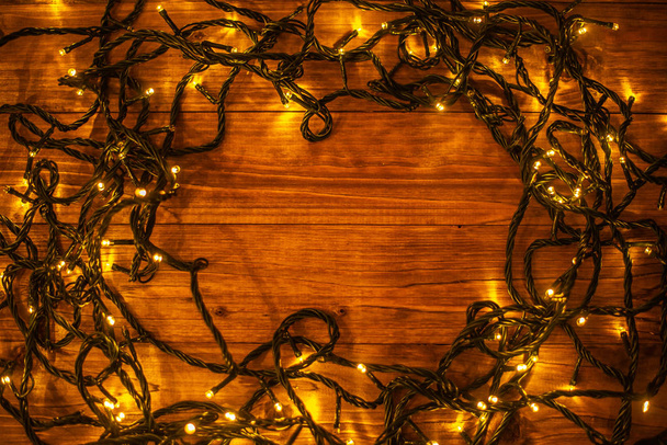 christmas background with illuminated festive garland on brown wooden background  - 写真・画像