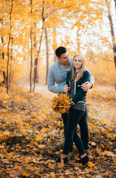 beautiful happy young couple standing together and hugging in autumn forest - Zdjęcie, obraz