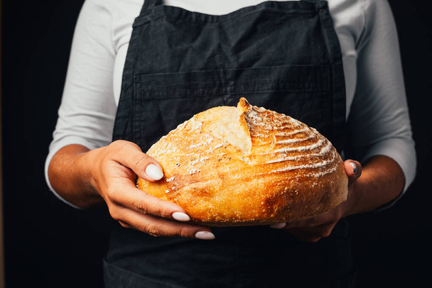 close-up partial view of baker holding freshly baked bread in hands - Foto, immagini