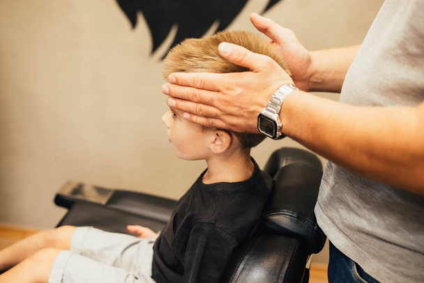 close-up partial view of adorable little boy getting a haircut at barber shop - Photo, image
