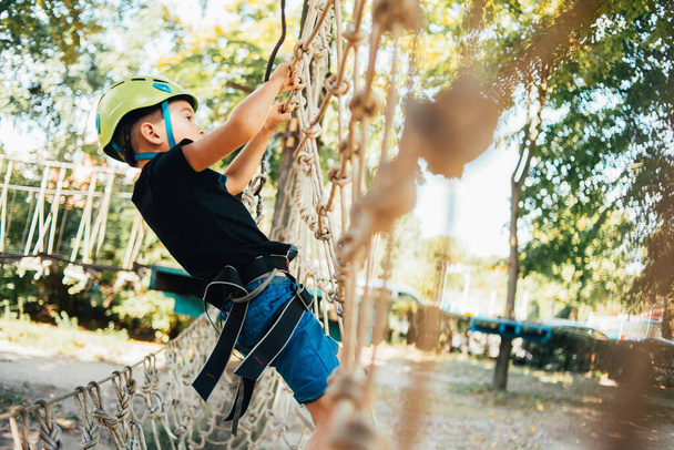 adorable happy boy enjoying activity in a climbing adventure park on a summer sunny day - Фото, зображення