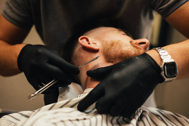 partial view of barber shaving beard to man in barbershop - Photo, image