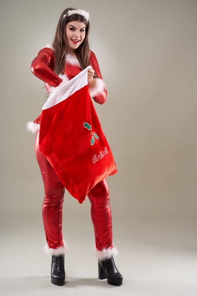 Full length of a Santa girl with a sack full of presents - Фото, изображение