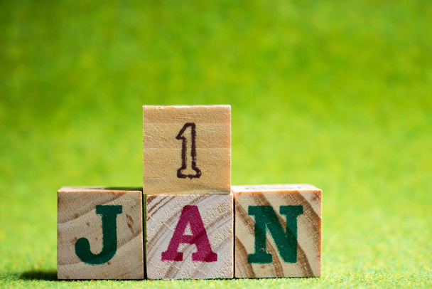 Letra de bloque en la palabra 1jan sobre fondo verde artificial (Concepto para la fecha del calendario en 1 mes enero, la primera fecha del año nuevo
) - Foto, imagen