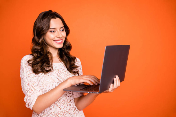 Portrait of positive cheerful girl use her computer have online conversation with friend on social media account wear good looking outfit isolated over orange color background - Foto, imagen