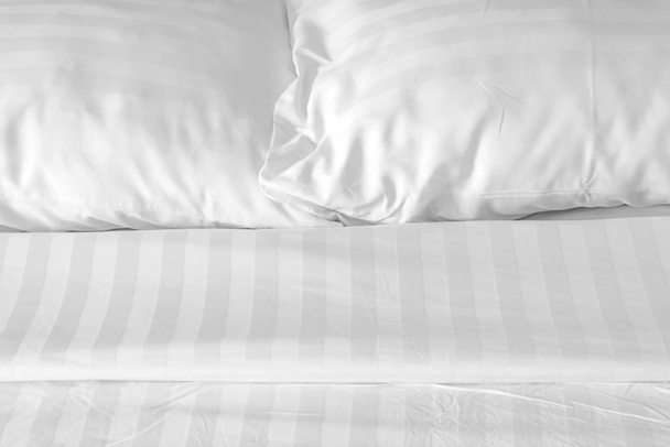 weißes Kissen mit chaotischer Decke auf dem Bett im Schlafzimmer aus nächster Nähe - Foto, Bild