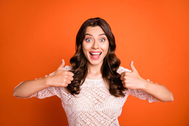 Portrait of amazed excited girl advertise show thumb-up sign suggest select promo wear knitted blouse isolated over orange color background - Foto, Imagem