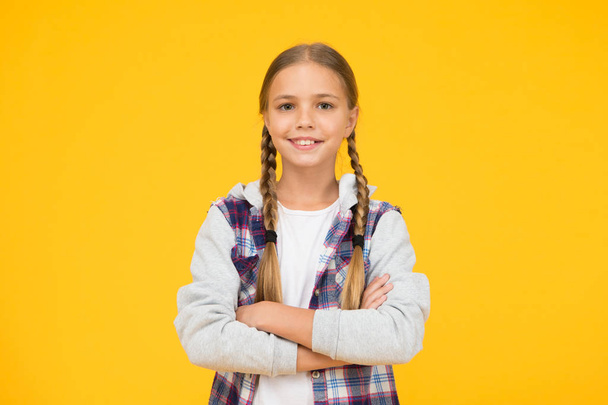 Casual style. Little girl yellow background. Good mood concept. Positive vibes. Self confidence. Cute braided girl. Kid long hair. Small girl checkered shirt. Happy international childrens day - Photo, Image