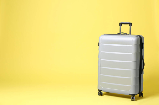 Stylish grey suitcase on yellow background. Space for text - 写真・画像
